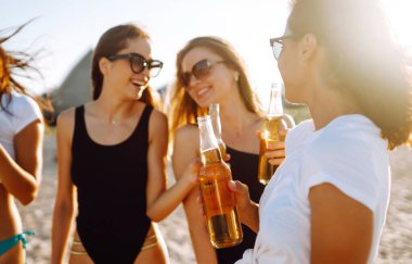 Dört güzel kız sahilde bira içip, eğleniyorlar. Tatil zamanı gülmek ve gülümsemek.