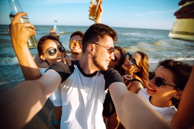 Bir grup genç arkadaş yaz tatilinde selfie çekiyorlar. Tatiller, rahatlama ve yaşam tarzı konsepti.
