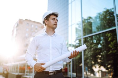 İş yerinde kask takan genç bir işçi. İnşaat alanında mühendis. İş, inşaat, evrak işleri ve insan konsepti.