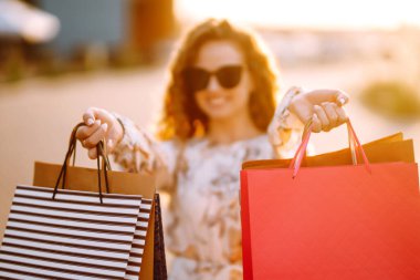 Alışveriş torbaları ellerde. Şehir caddesinde alışveriş torbaları tutan güzel bir kız. Tüketim, alışveriş, satış, yaşam tarzı konsepti.