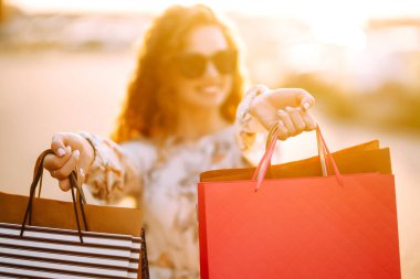 Alışveriş torbaları ellerde. Şehir caddesinde alışveriş torbaları tutan güzel bir kız. Tüketim, alışveriş, satış, yaşam tarzı konsepti.