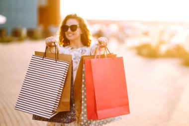 Alışveriş torbaları ellerde. Şehir caddesinde alışveriş torbaları tutan güzel bir kız. Tüketim, alışveriş, satış, yaşam tarzı konsepti.