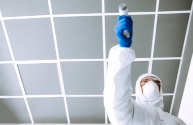 Ofisteki sıcaklığı kontrol etmek için kızılötesi termometre cihazlı bir hastalık kontrol uzmanı. Salgının yayılmasını önleme ve koronavirüsü tedavi etme kavramı karantinada salgındır. 