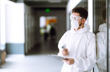 Sıcaklığı kontrol etmek için kızılötesi termometre cihazlı bir hastalık kontrol uzmanı. Salgının yayılmasını önleme ve koronavirüsü tedavi etme kavramı karantina şehrinde salgındır.. 