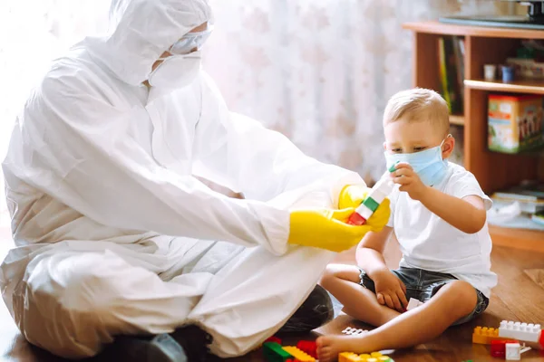 防護ハズマットスーツの男は医療マスクの小さな子供とコンストラクタを果たしている 感染症の拡大を防止し コロナウイルスを治療するという概念 検疫都市のパンデミック Covid — ストック写真