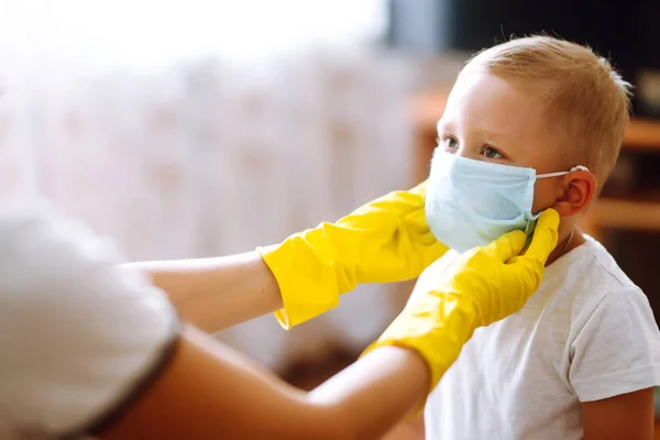 Mother Yellow Gloves Puts Her Baby Sterile Medical Mask Concept — Stock Photo, Image