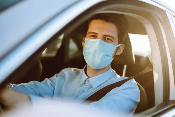 流行の間に医療用マスクに身を包んだ車を運転する男 マスクの運転手 タクシー Covid 2019 — ストック写真