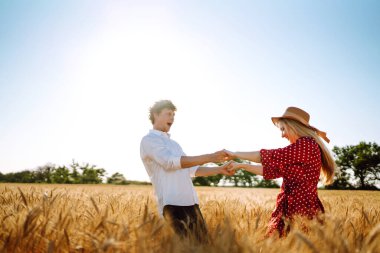 Bir çift buğday tarlasında eğleniyor ve dinleniyor. Genç kız arkadaş ve erkek arkadaş öpüşüyor ve sarılıyorlar. Gençlik, aşk ve yaşam tarzı kavramı.