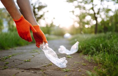 Parkta boş plastik şişeler. Parkta çöp toplama. Koruyucu eldiven giyen erkekler şişe plastiği toplar. Doğayı kurtar.