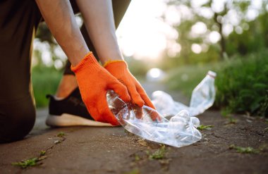 Parkta boş plastik şişeler. Parkta çöp toplama. Koruyucu eldiven giyen erkekler şişe plastiği toplar. Doğayı kurtar.