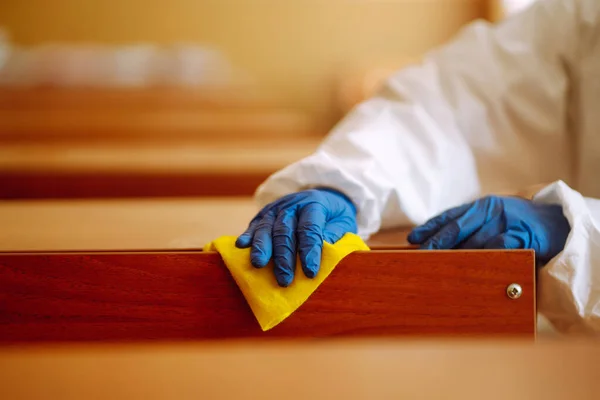 Cleaning and disinfection school class to prevent COVID-19. Man in protective hazmat suit washes school desk  to preventing the spread of coronavirus, pandemic in quarantine city.