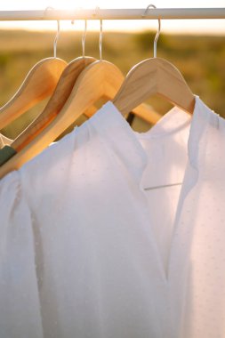 Askıdaki zarif yaz elbiseleri. Altın buğday tarlasının arka planı. Moda, tarz, yaşam tarzı konsepti.