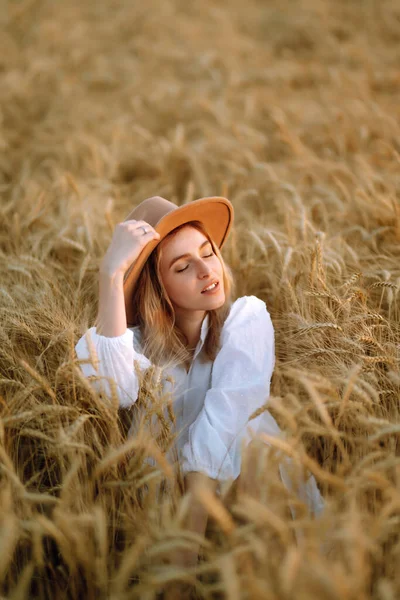 穿着夏装 头戴白帽 衣着时髦的小女孩在金黄色的麦田里摆姿势 生活方式概念 — 图库照片