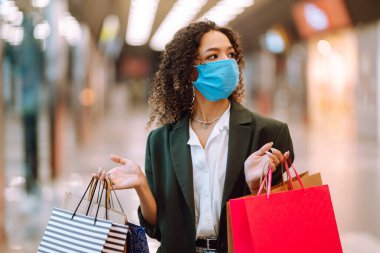 Coronavirus salgını sırasında alışveriş yaptıktan sonra maske takan genç bir kadın. Covid 2019.