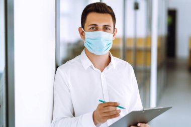 Bir salgın sırasında ofiste steril maske takan bir ofis çalışanı. COVID-19. İş konsepti. 