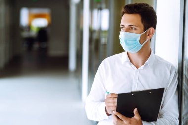 Bir salgın sırasında ofiste steril maske takan bir ofis çalışanı. COVID-19. İş konsepti. 