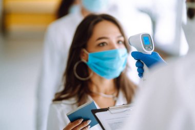 Ofisteki çalışanların sıcaklığını ölçmek için termometre tabancası Isometric Medical Digital. Covid 19.