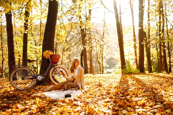 秋の公園に座っている美しい若い女性は 本を読んで 休息と自由を楽しむ自転車で笑顔の女の子 リラクゼーションとライフスタイルのコンセプト — ストック写真