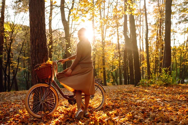 日没の秋の森の中で自転車に乗っている若い女の子 — ストック写真