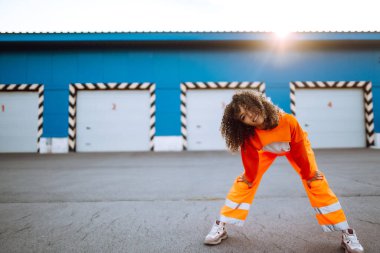 Afrika kökenli Amerikalı bir kız. Gün batımında sokakta dans ediyor. Spor, dans ve şehir kültürü konsepti. Moda yaşam tarzı.