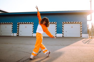 Afrika kökenli Amerikalı bir kız. Gün batımında sokakta dans ediyor. Spor, dans ve şehir kültürü konsepti. Moda yaşam tarzı.