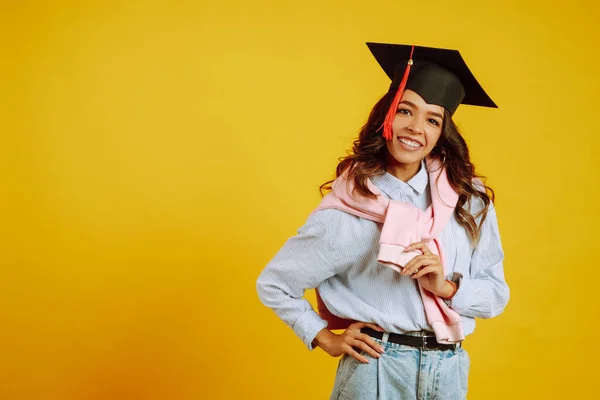 黄色の背景にポーズをとっている彼女の頭の上に卒業帽子のアフリカ系アメリカ人の少女の肖像 遠隔教育の概念 — ストック写真