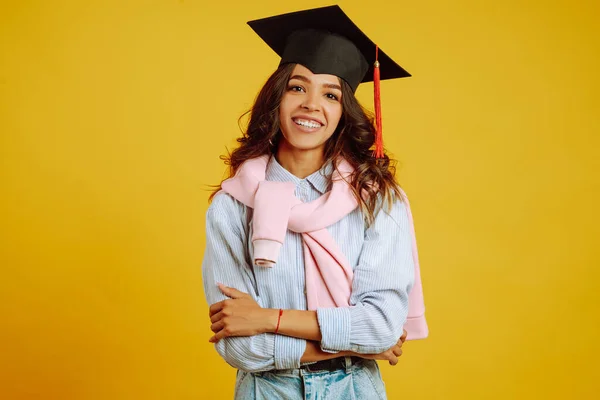 黄色の背景にポーズをとっている彼女の頭の上に卒業帽子のアフリカ系アメリカ人の少女の肖像 遠隔教育の概念 — ストック写真