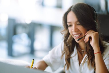 Genç kız öğrenci internetten kablosuz kulaklık dersi alıyor. Dil öğreniyor. Ders dinliyor. Webinar 'ın not yazışını izliyor. Ncov durumu sırasında video çağrısı