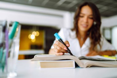 Dişi el elinde fosforlu kalem, çalışma kağıtlarındaki önemli metinleri işaretleme / işaretleme. Genç kız öğrenci çevrimiçi çalışıyor. Uzak eğitim.