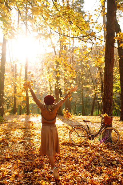 Beautiful Woman throws up autumn leaves and having fun  in autumn park. Relaxation, enjoying, solitude with nature.