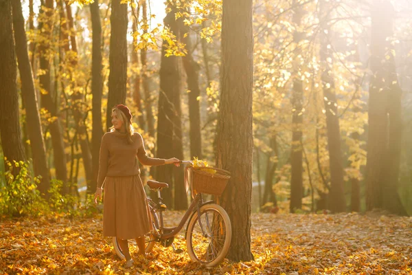 公園で秋の天気を楽しむ自転車とスタイリッシュな女性 夕日の秋の森を歩く美しい女性 — ストック写真