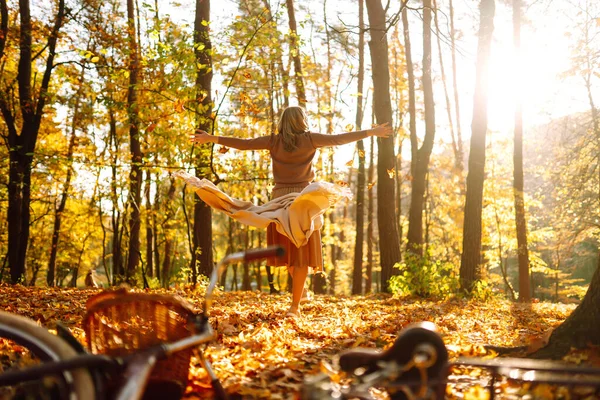 Beautiful Woman throws up autumn leaves and having fun  in autumn park. Relaxation, enjoying, solitude with nature.