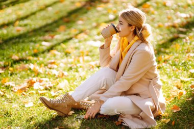 Güz parkında kahve içen güzel kadın. Rahatlama, keyif alma, doğayla baş başa kalma..