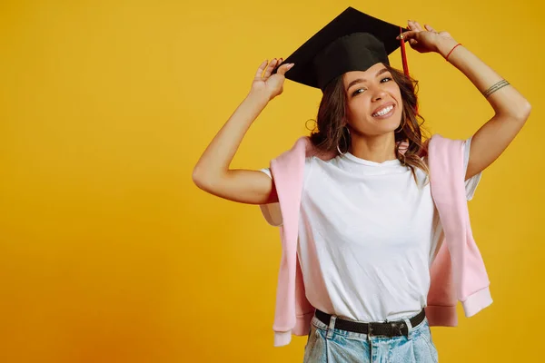 黄色の背景にポーズをとっている彼女の頭の上に卒業帽子の大学院生の女性 大学院の概念 — ストック写真