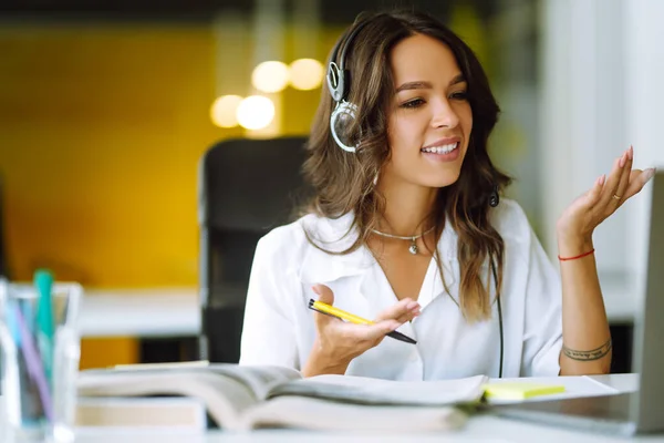 Distance learning. Young business woman, student, teacher, tutor wear wireless headset video conference calling on laptop computer talk by webcam.