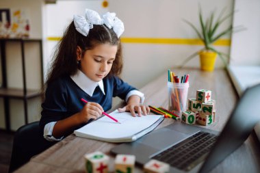 Çevrimiçi uzaktan öğrenme. Bilgisayarlı liseli kız öğretmenle görüntülü konuşma yapıyor. Güzel kız resim çizer ve ödev çalışır. Covid 2019.
