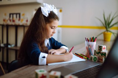 Çevrimiçi uzaktan öğrenme. Bilgisayarlı liseli kız öğretmenle görüntülü konuşma yapıyor. Güzel kız resim çizer ve ödev çalışır. Covid 2019.