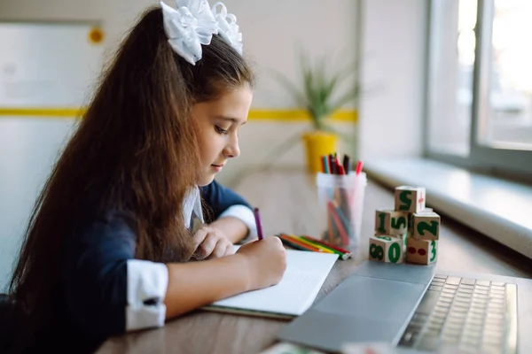 Online remote learning. School girl in with computer having video conference chat with teacher. Beautiful girl draws and studying homework. Covid-2019.
