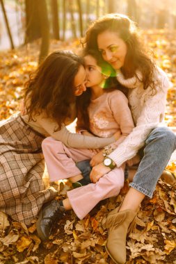 Güzel bir çift lezbiyen kız evlatlık kızlarıyla sonbahar ormanında eğleniyor. Genç homoseksüel aile kızıyla oynuyor.. 
