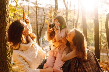 Güz ormanlarında retro kamerayla eğlenen güzel bir çift lezbiyen kadın. Genç homoseksüel aile ve evlatlık genç kızları fotoğraf için poz veriyorlar..