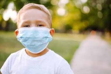 Little boy in medical face mask in the park at sunset. Virus and illness protection. Covid-2019. Kids safety.  clipart