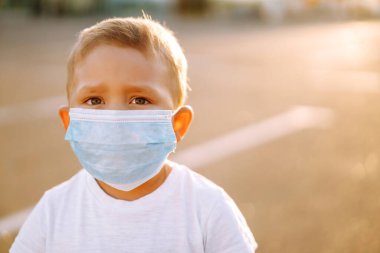 Little boy in medical face mask  in the city. Virus and illness protection. Covid-2019. Kids safety. clipart