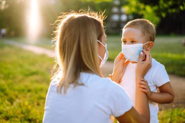 Anne parkta çocuk steril tıbbi maskesini takıyor. Coronavirus 'tan sağlık ve güvenlik hayatı kavramı. Covid-2019. Çocukların güvenliği için. Virüs ve hastalık koruması.