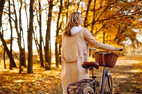 Осенняя женщина в осеннем парке. Счастливая молодая женщина позирует с велосипедом в осеннем лесу.