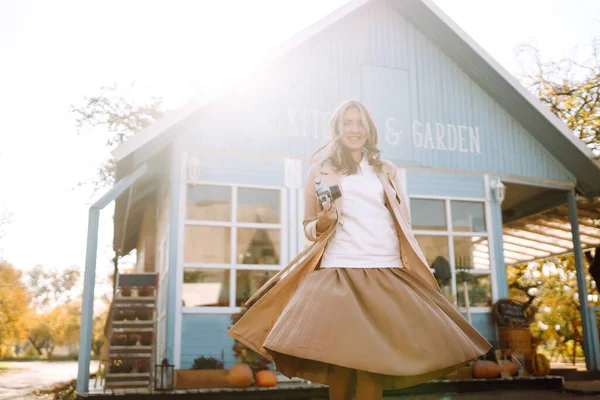 Mavi bir evin arka planında klasik kamerası olan güzel bir kadın. Sonbahar moda konsepti.