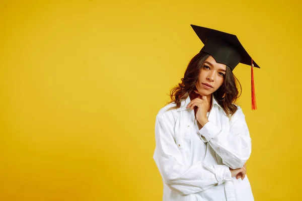 Portrait of Graduate woman in a graduation hat and in white shirt.  Study, education, university, college, graduate concept on yellow banner.