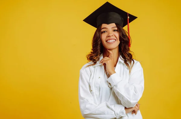 Portrait of Graduate woman in a graduation hat and in white shirt.  Study, education, university, college, graduate concept on yellow banner.