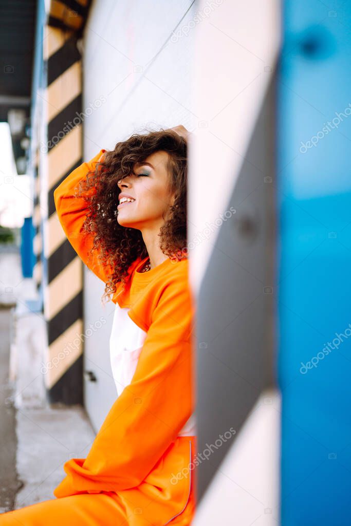 Beautiful dancer woman on a street in orange suit. African American woman dancing at sunset. Sport, dancing and urban culture concept.