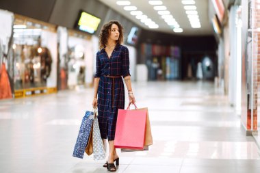 Alışveriş merkezinde alışveriş yapan gülümseyen bir kadın. Alışveriş sonrası paketleri olan genç bir kadın. Satın almalar, Kara Cuma, indirimler, satış konsepti.