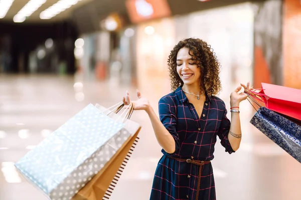 Smiling woman with shopping bags enjoying shopping in the mall.Young woman with packages after shopping. Purchases, black friday, discounts, sale concept.